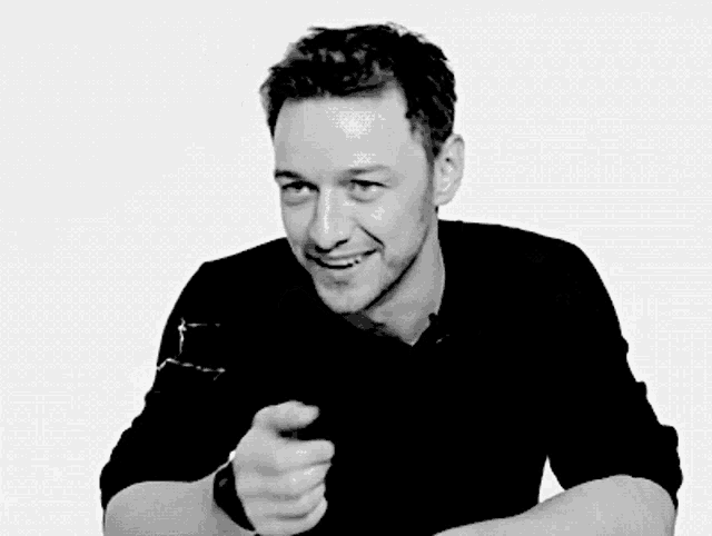 a man wearing a black shirt is pointing at the camera
