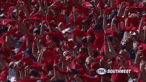 a crowd of people are waving red scarves in the air at a soccer game .
