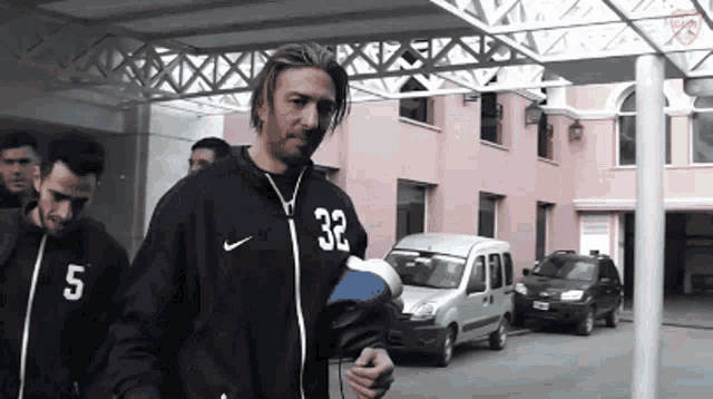 a man wearing a nike jacket with the number 32 on the front