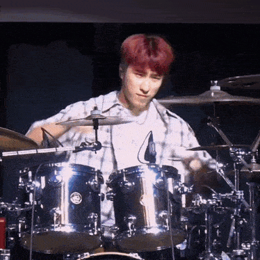 a man is playing drums on a stage in a dark room .