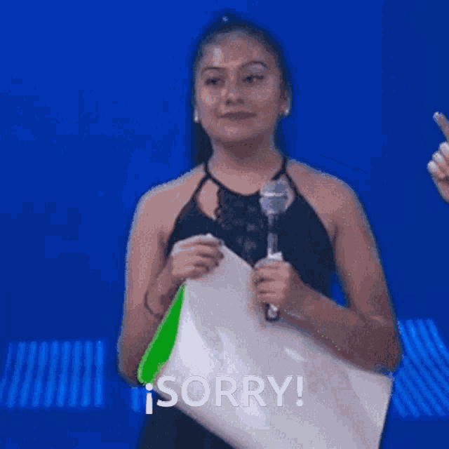 a woman in a black dress is holding a microphone and saying sorry ..