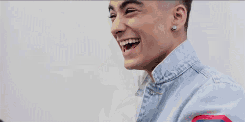 a man wearing a red hoodie and a black jacket is laughing with his mouth open
