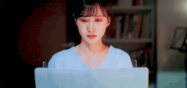 a woman is crying while looking at a laptop computer .