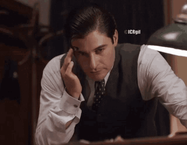 a man in a suit and tie looks at himself in a mirror with icrgif written above him