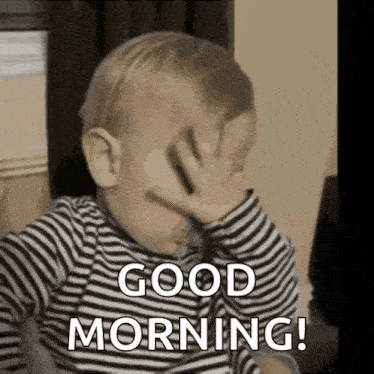 a baby in a striped shirt is covering his face with his hand and saying `` good morning '' .
