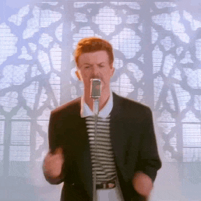 a man in a suit and striped shirt is singing into a microphone in front of a window .