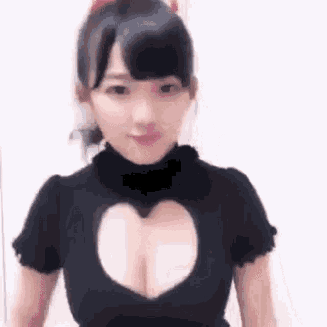 a woman wearing a black shirt with a heart shaped cut out in the chest .