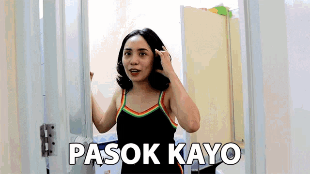 a woman in a rainbow tank top is standing in a doorway with the words pasok kayo written on it .