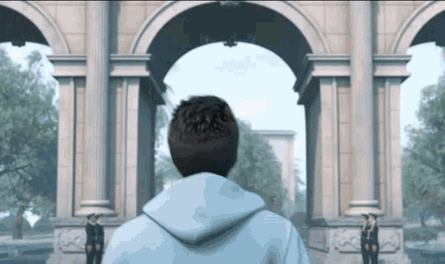 a man in a white hoodie is standing in front of a large archway