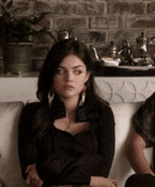 two women are sitting on a couch with their arms crossed