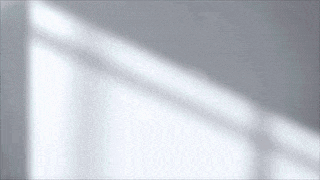the shadow of a window is cast on a gray wall .
