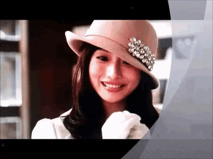 a woman wearing a pink hat with rhinestones on it is smiling .