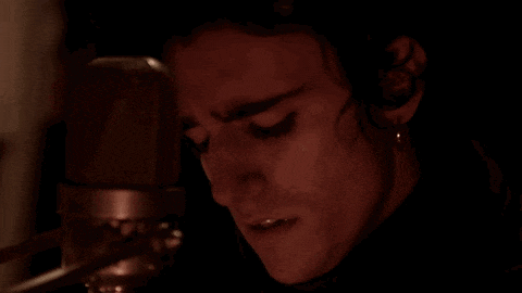 a woman is singing into a microphone in the dark