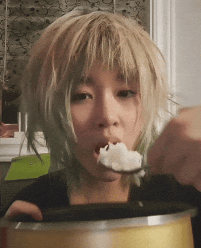 a woman with blonde hair is eating rice from a can with a spoon