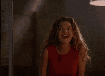 a woman in a red dress is standing in a dark room with her hair in the air .
