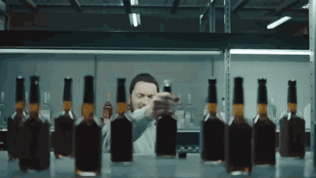 a man is standing in front of a row of bottles of liquor .