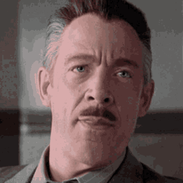 a close up of a man with a mustache wearing a suit and tie .