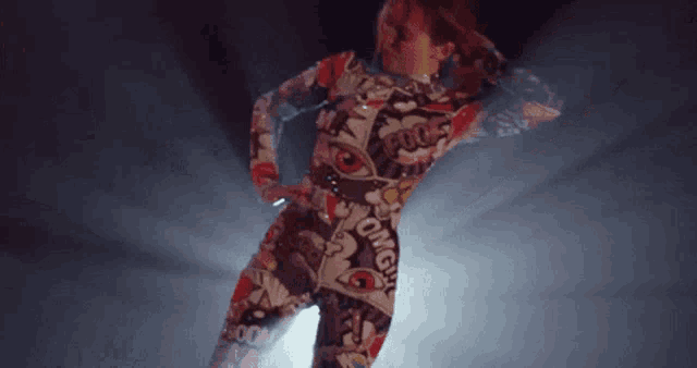 a woman in a colorful costume is dancing on a stage in a dark room .