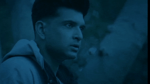 a man holds his finger to his mouth in a dark room