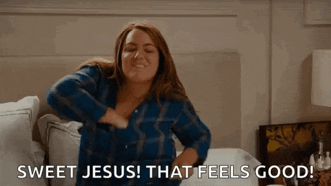 a woman is sitting on a bed with her hands on her chest and says sweet jesus ! that feels good .