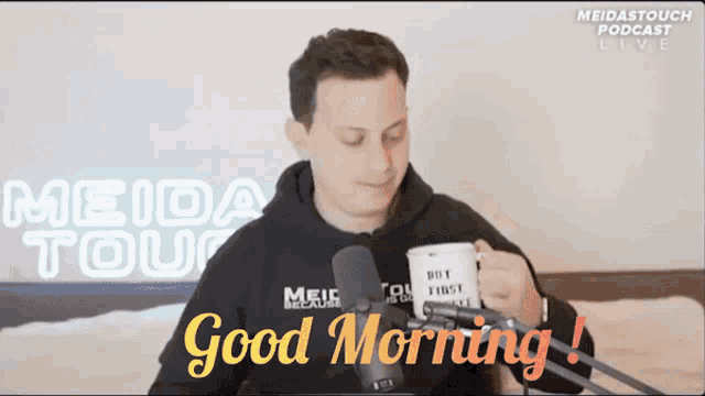 a man is holding a mug in front of a microphone and says good morning on the bottom