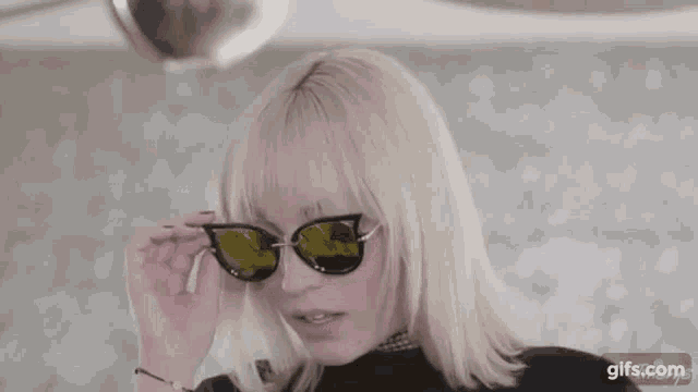 a woman with blonde hair is wearing sunglasses and a choker .