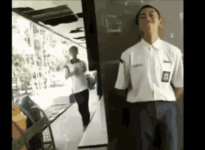 a man in a white shirt is standing in front of a door .
