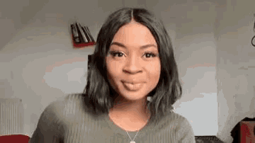 a woman wearing a green sweater and a necklace is smiling at the camera .