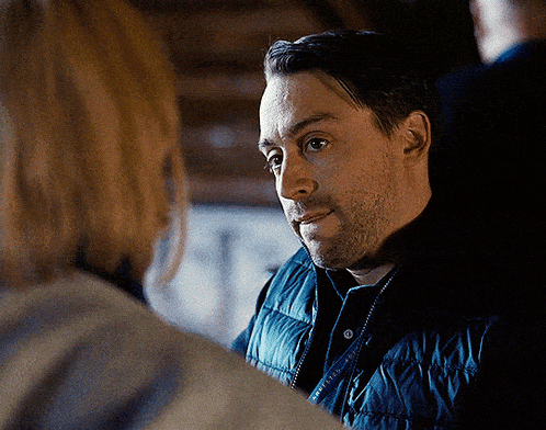 a man wearing a blue vest is talking to another man
