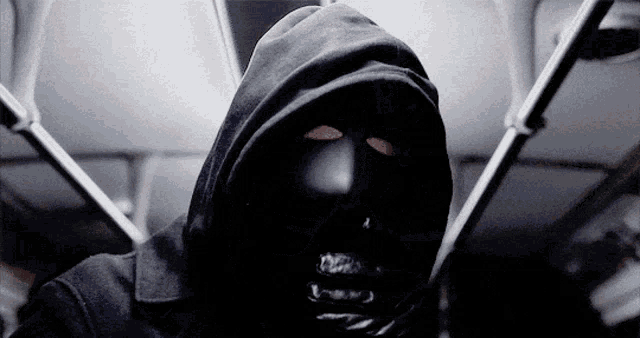 a man wearing a black hooded jacket and a black mask