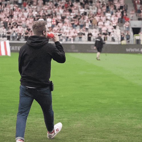 a man stands on a soccer field holding a microphone