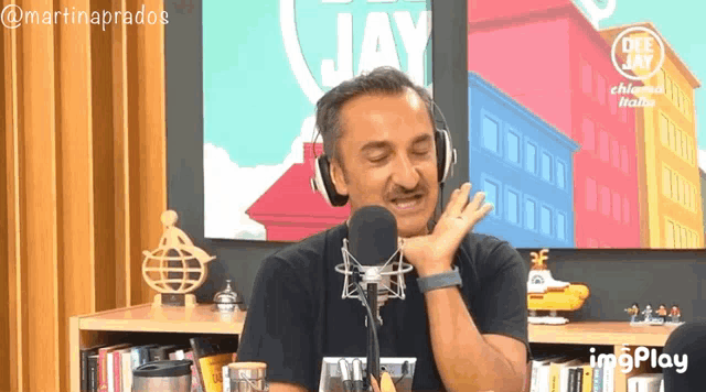 a man wearing headphones talks into a microphone in front of a sign that says off jay