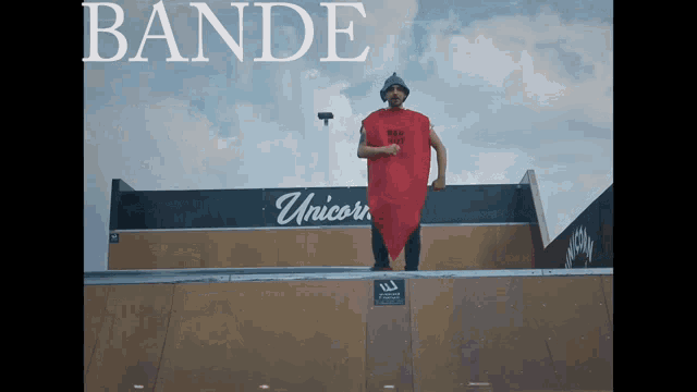 a man in a red cape stands on a ramp in front of a unicorn sign