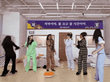 a group of women are dancing in front of a sign that says ' jee '