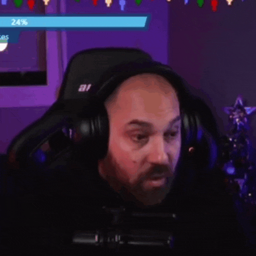 a man with a beard is wearing headphones and sitting in a gaming chair .