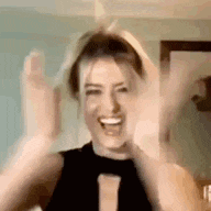 a woman is making a funny face with her hands in the air and smiling .