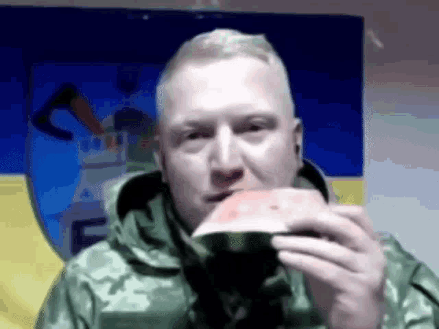 a man is eating a watermelon in front of a flag .
