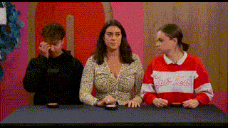 a group of people are sitting at a table and one of them is wearing a red sweater that says club ted .