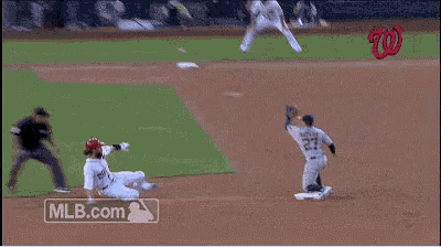 a baseball player with the number 28 on his jersey is sliding into second base