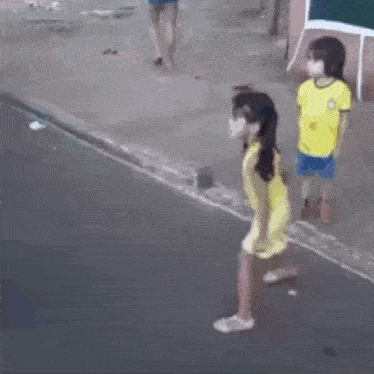 a group of children are standing on a sidewalk holding hands .