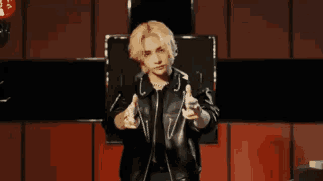 a man in a leather jacket is holding a red heart shaped object in his hands .