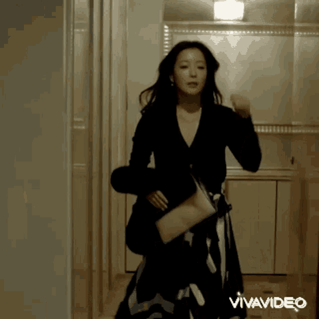 a woman in a black dress is dancing in a hallway with vivavideo written in the corner