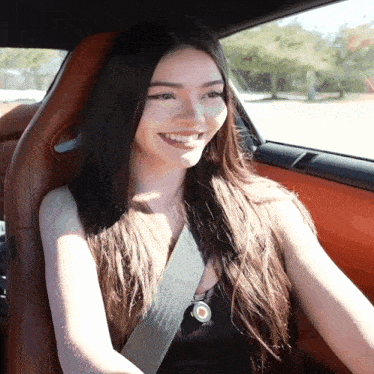 a woman wearing a seat belt is smiling while sitting in a car