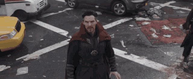 doctor strange is standing in the middle of a busy city street surrounded by cars .