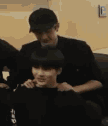 a man in a baseball cap is sitting next to a boy in a black sweater .