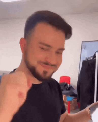a man with a beard is making a funny face while sitting in front of a laptop computer .