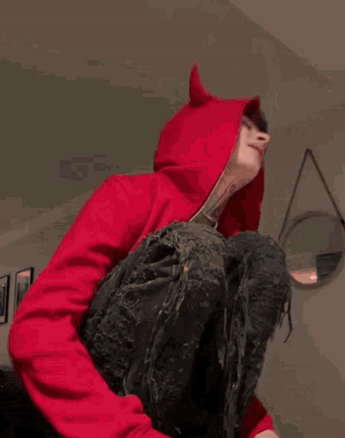a young boy wearing a red hoodie with horns on it