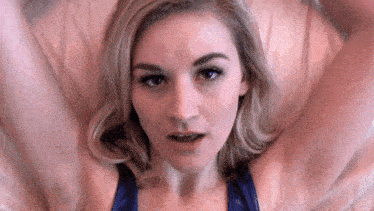 a woman is laying on a bed with her arms outstretched and her mouth open .