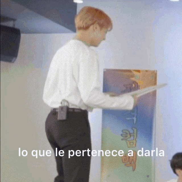 a man in a white shirt and black pants is standing in front of a sign that says lo que le pertenece
