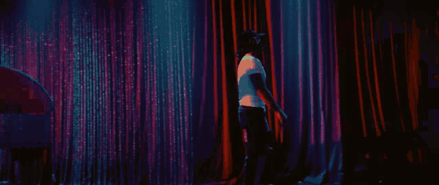 a man in a white shirt stands in front of a red and blue curtain